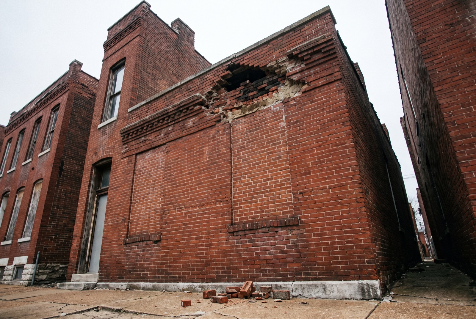A brick cornice with a gap where bricks have fallen to the sidewalk
