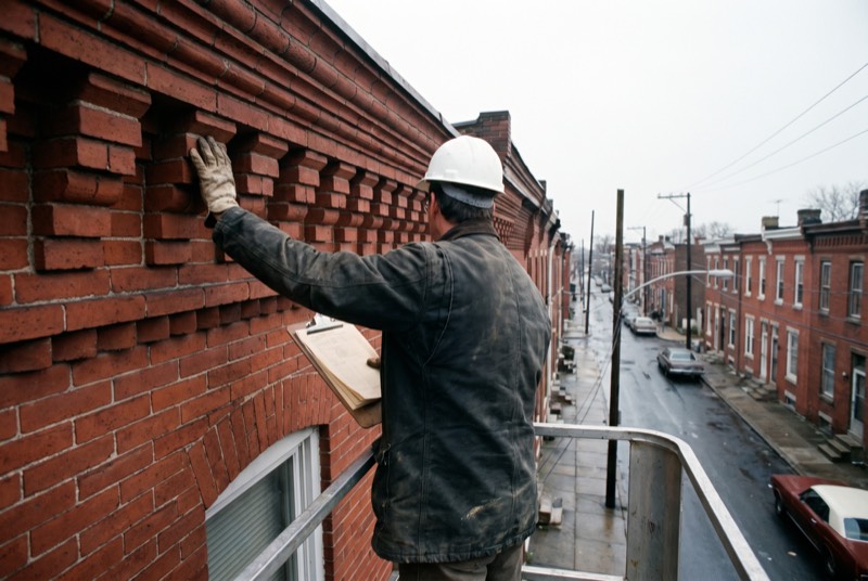 An engineer in a lift basket beside a brick cornice