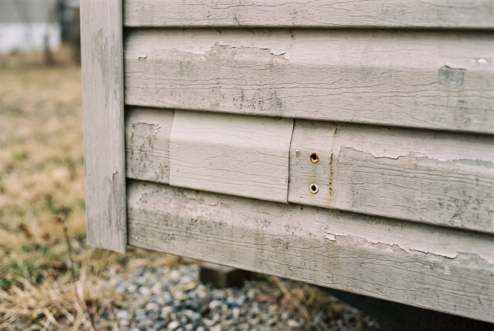 The corner of a manufactured home where a tag is missing, leaving two rivet holes