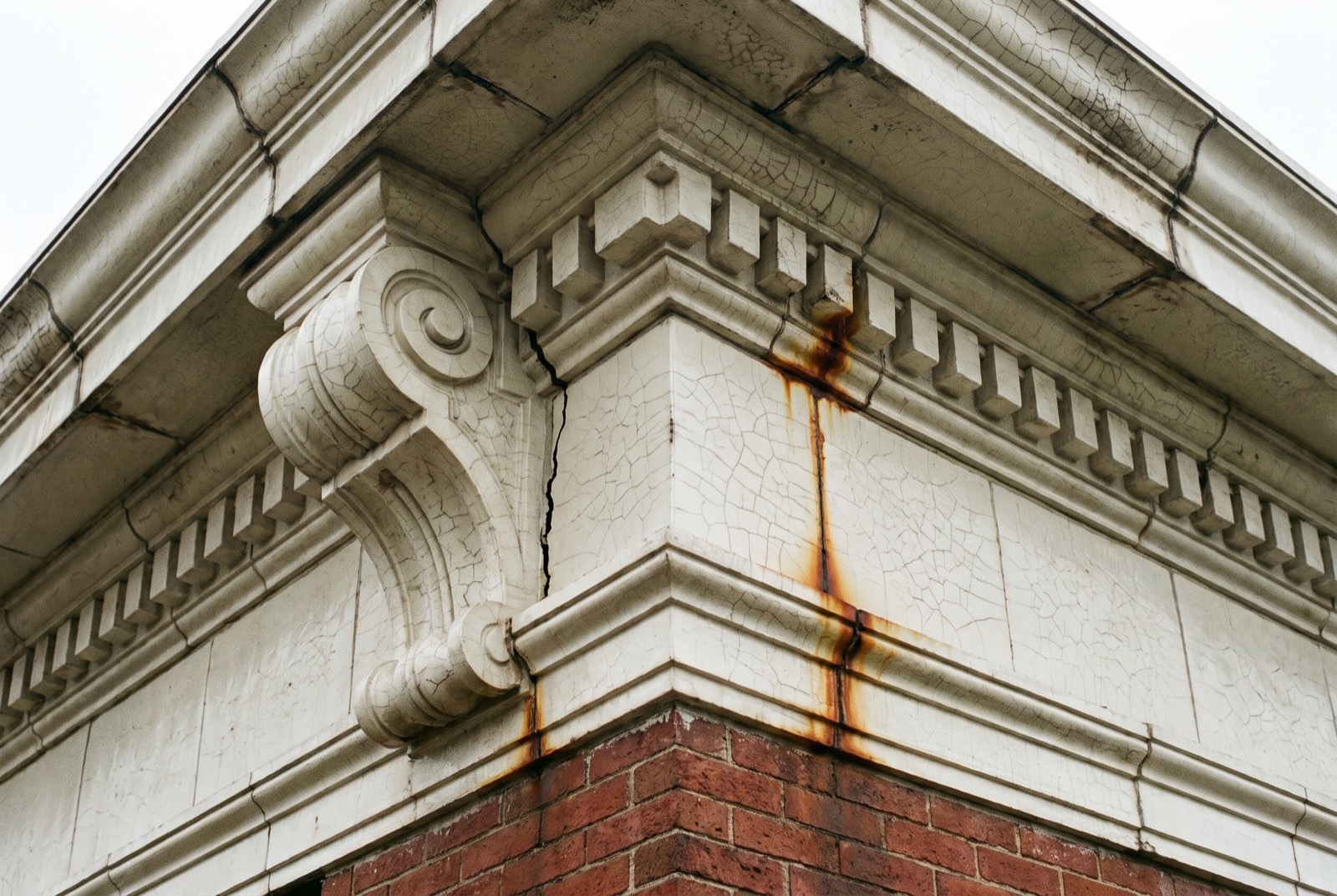 A glazed terra cotta cornice with a cracked block and rust stains