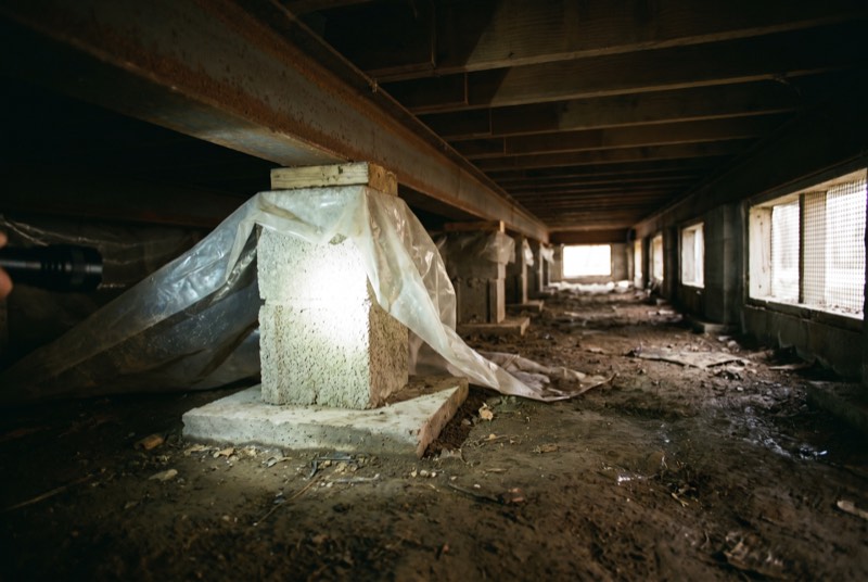 Concrete block piers and steel beams in the crawl space under a manufactured home