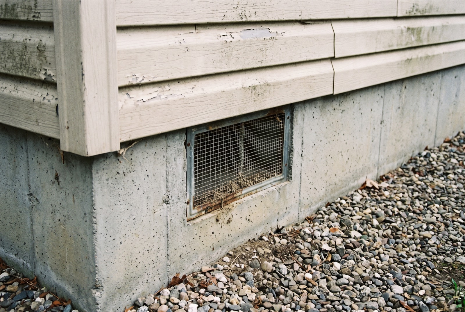 The corner of a manufactured home on a poured concrete perimeter foundation with a screened vent